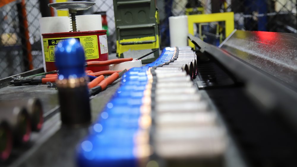 Blue-bodied 40mm grenade training rounds moving along a production line at Iowa Army Ammunition Plant