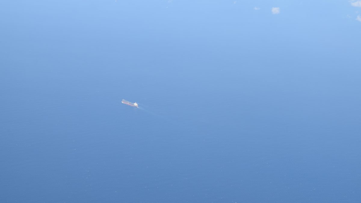 Aerial view of the Lombok Strait from above, showing a vessel transiting the deep blue waters between Bali and Lombok, Indonesia