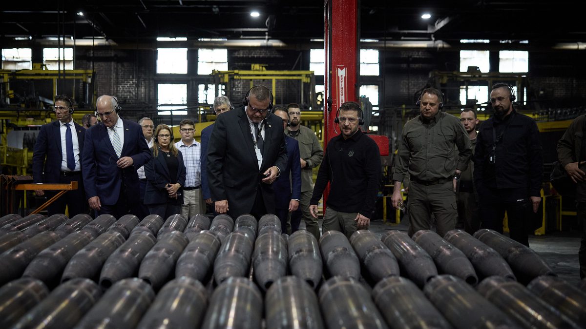 Rows of 155mm artillery projectiles on pallets inside a large US Army ammunition plant production hall &mdash; representative of the scale of modern energetics and munitions manufacturing.