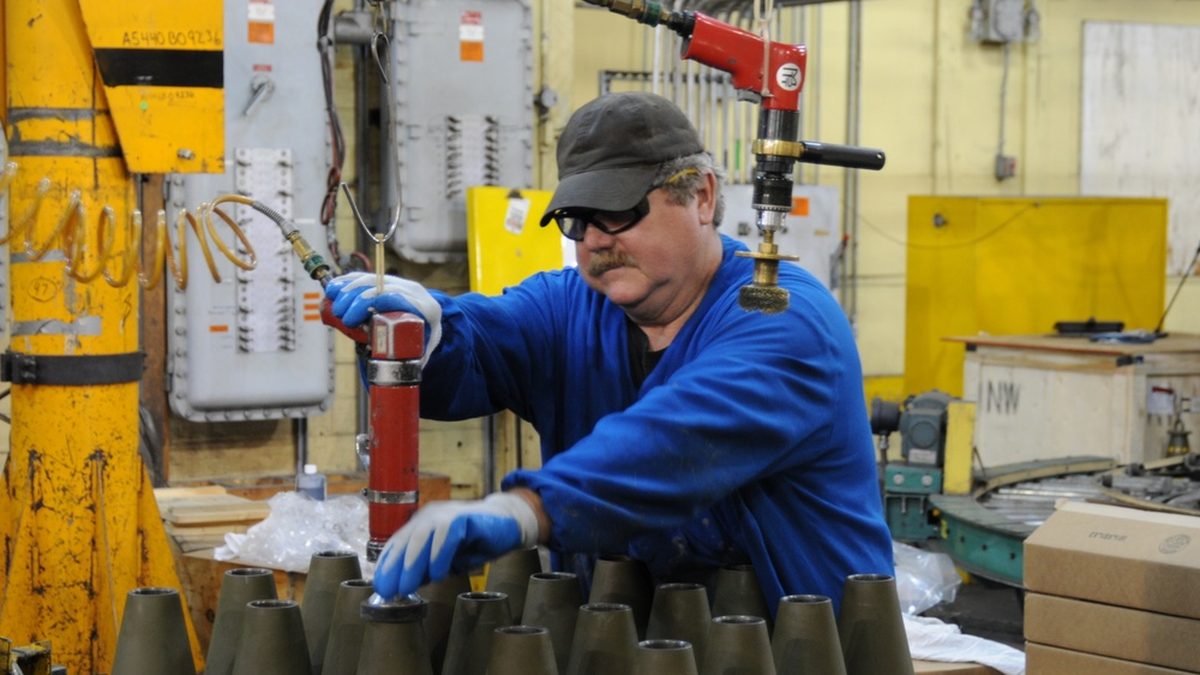 A contractor employee performs load, assemble and pack operations on a 155mm artillery round at Iowa Army Ammunition Plant
