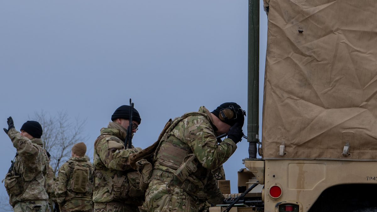 U.S. Soldiers from 3rd Brigade, 10th Mountain Division, setting up Starshield communications equipment alongside a tactical vehicle during a cold-weather NATO exercise in Germany.