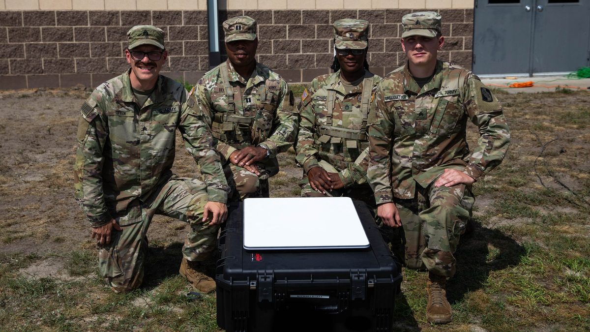U.S. Army Soldiers of the 324th Expeditionary Signal Battalion pose with a SpaceX Starshield UAT-222 terminal deployed on its transit case.