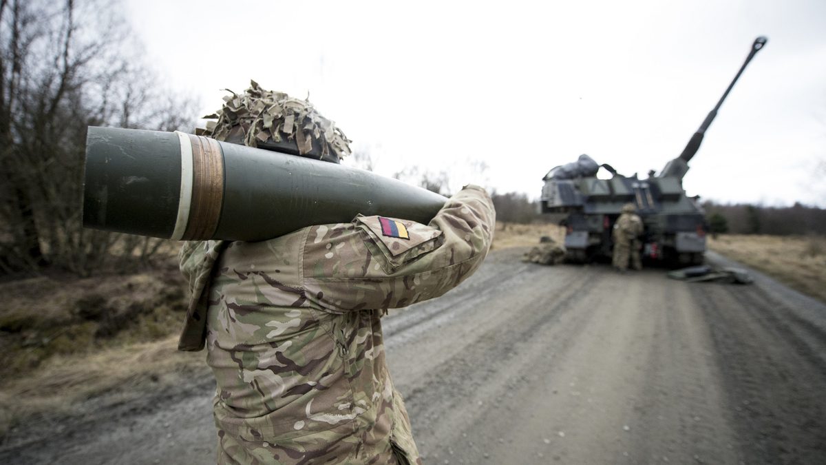 A British Army crew member of an AS90 self-propelled howitzer moves a 155 mm round prior to fuzing during Exercise Steel Sabre.