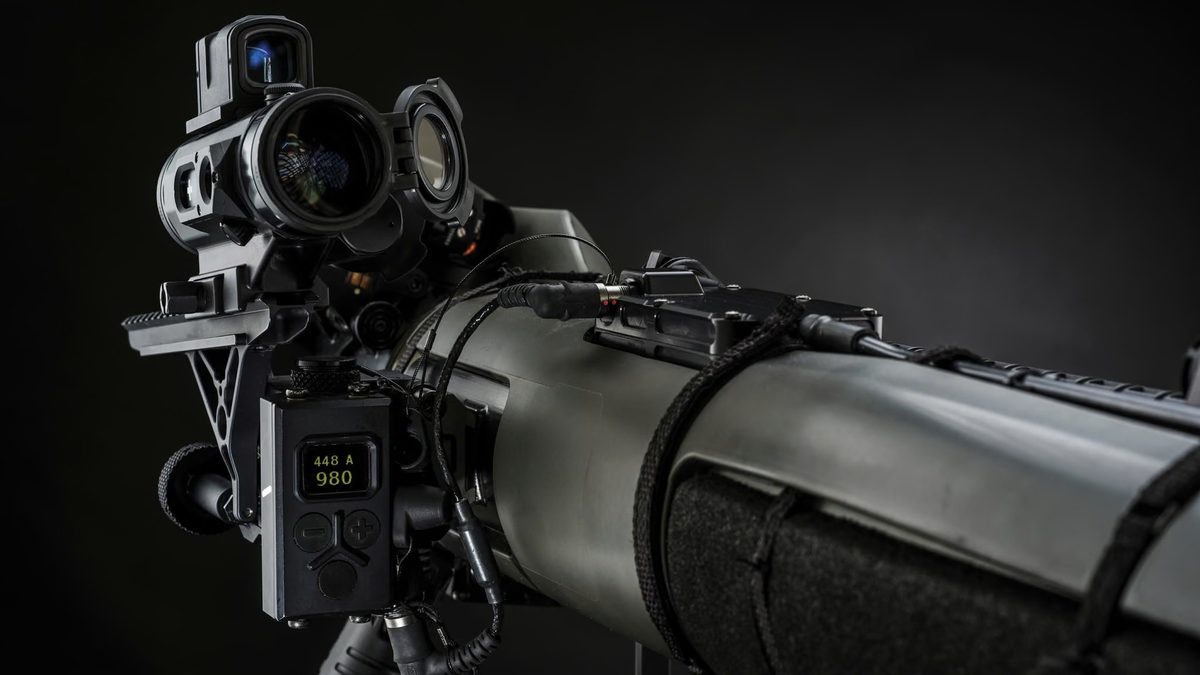 Operator in firing position with the Carl-Gustaf M4 84&nbsp;mm recoilless weapon, showing the launch tube and a chambered round with rounded nose.