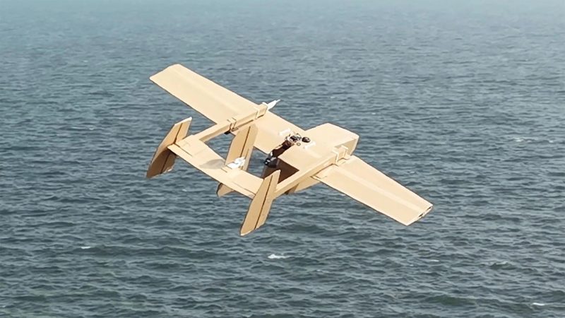 A twin-boom Corvo PPDS variant in flight low over open water, illustrating the Slow-Low-Small engagement profile that complicates radar-only counter-UAS architectures.