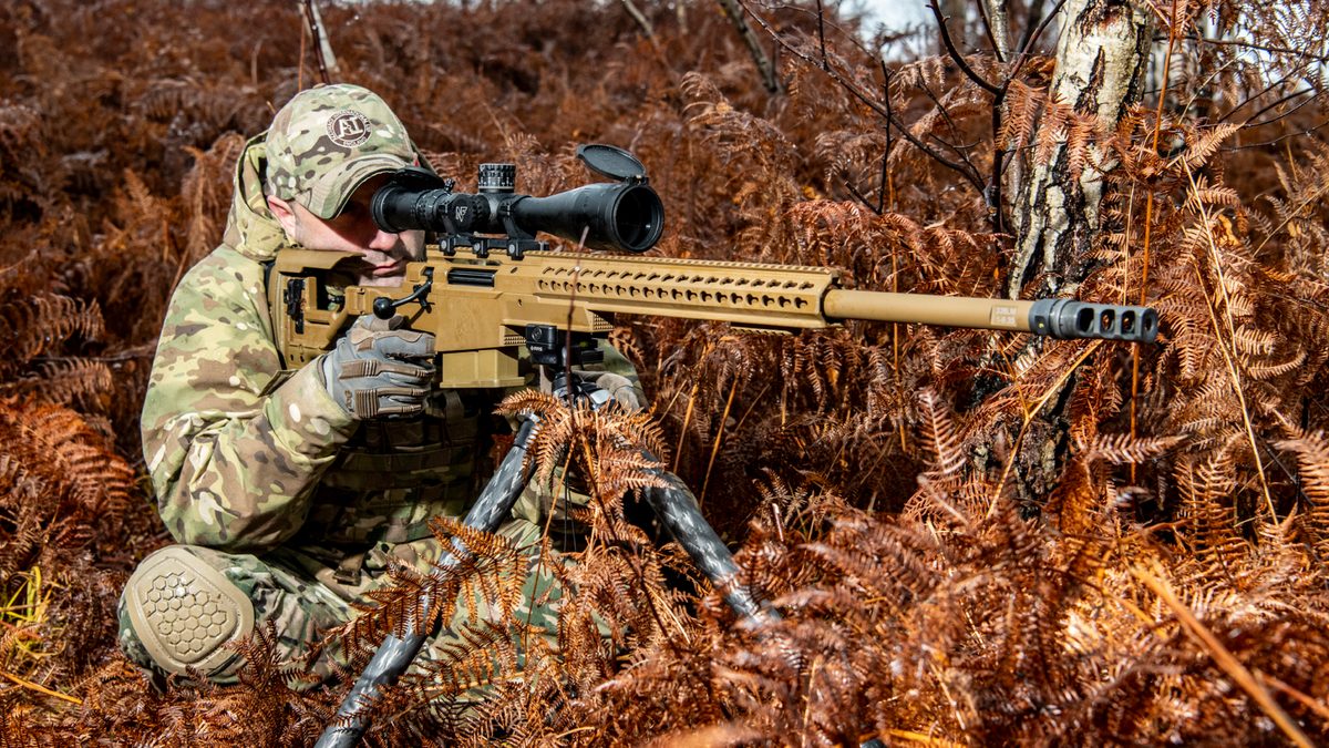 A marksman fires a desert-tan Accuracy International AXSR bolt-action precision rifle.
