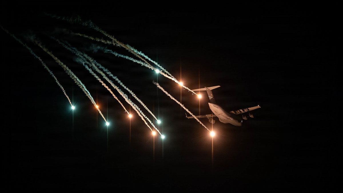 A US Air Force C-17 Globemaster III releases bright defensive flares against a night sky during testing