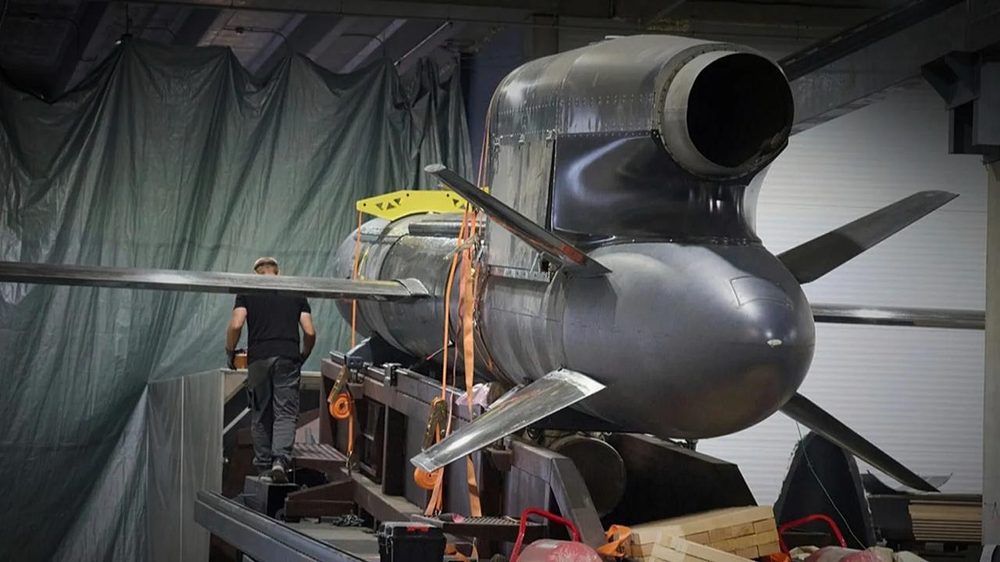 A large FP-5 Flamingo cruise missile under assembly in a workshop, with a worker alongside for scale