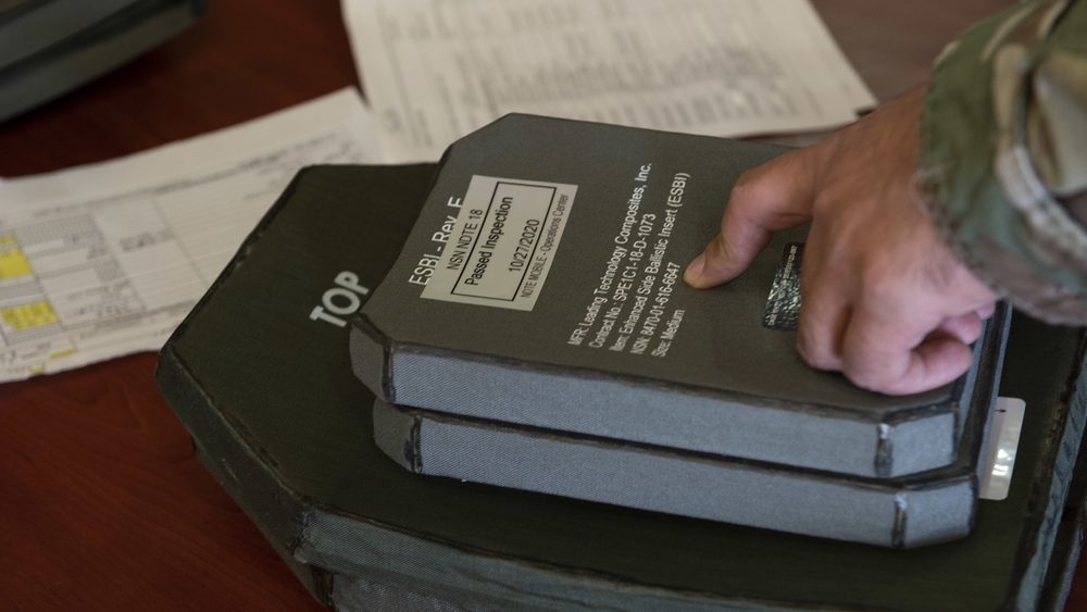 Airman checking the serial number and inspection stamp on a ceramic armour plate data tag