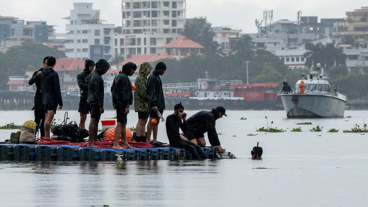 US and Indian Navy divers on a floating dive platform at Kochi, a diver in the water and an Indian patrol craft beyond