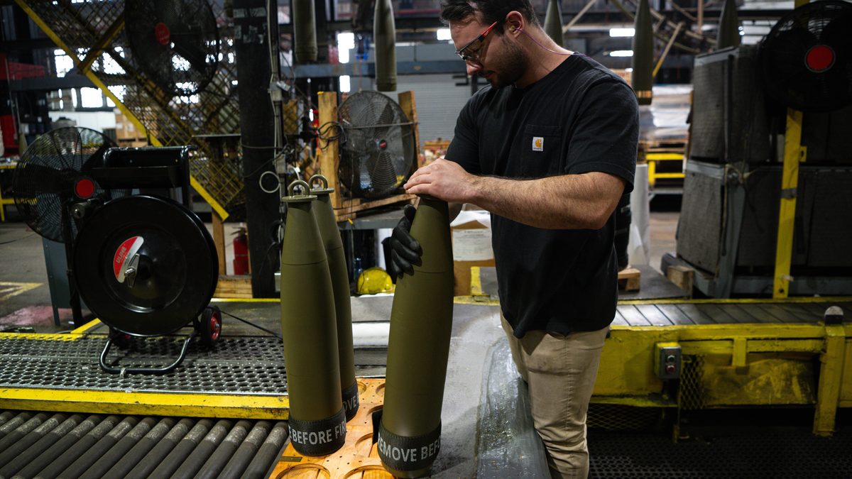 A plant employee prepares 155mm artillery projectiles on a production line at Scranton Army Ammunition Plant