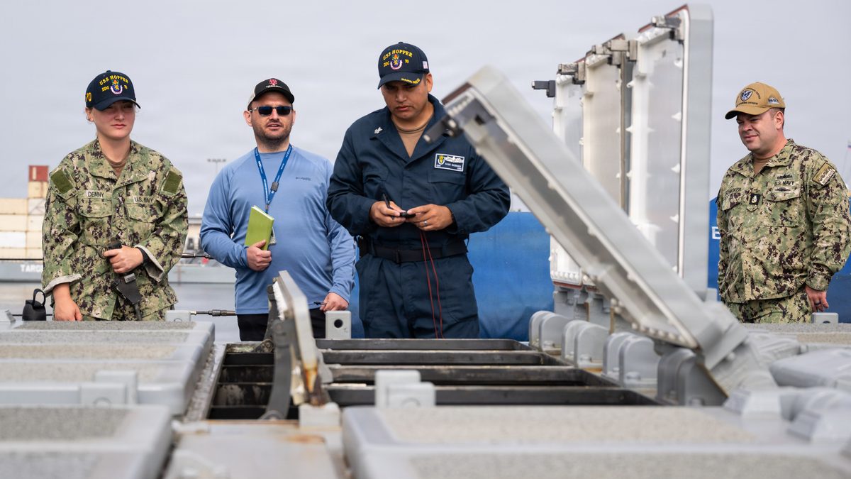 US Navy sailors and an engineering agent maintain open Mark 41 vertical launch cells aboard USS Hopper